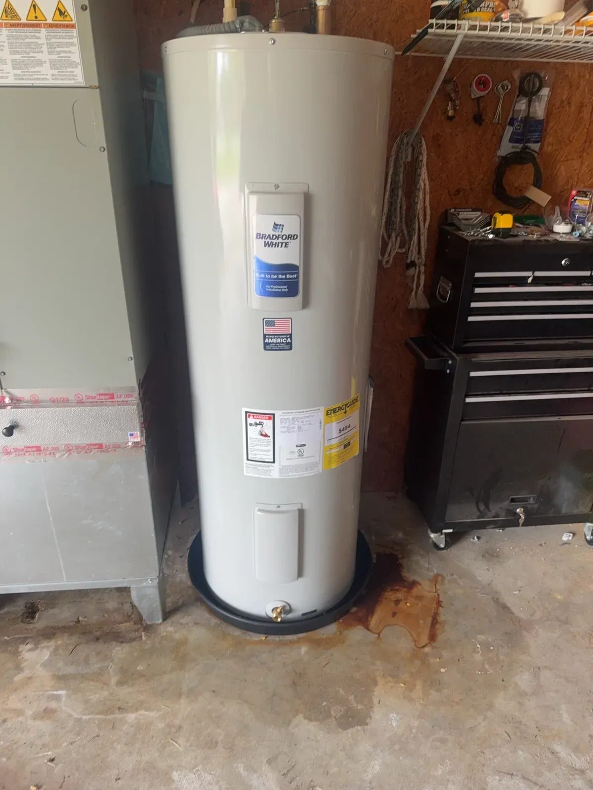 New Bradford White electric water heater in a drain pan in a garage, next to the air handler