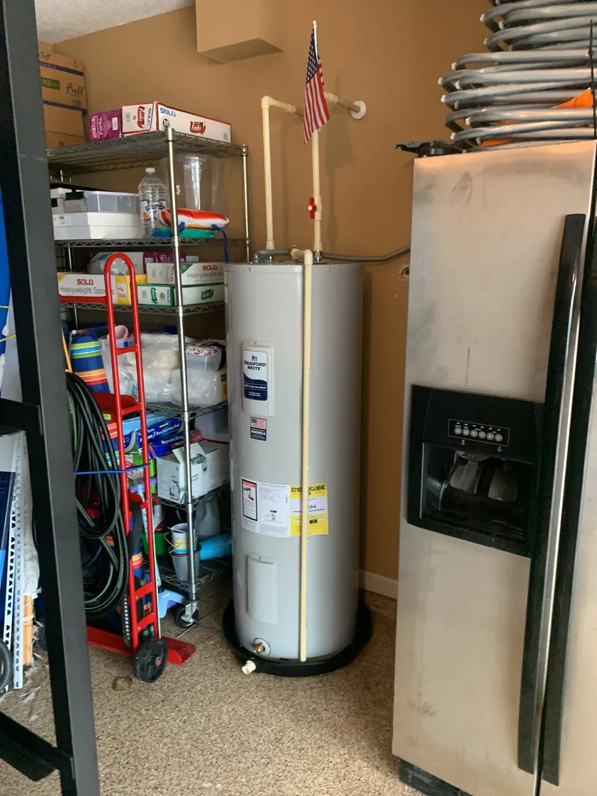 Electric tank water heater on a drain pan with supply piping and relief line